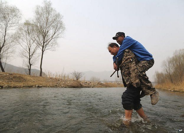 disabled men one blind, one a double amputee, planting trees together in rural China