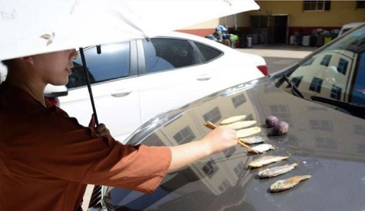  A woman fries fish on a burning hot car bonut at china 