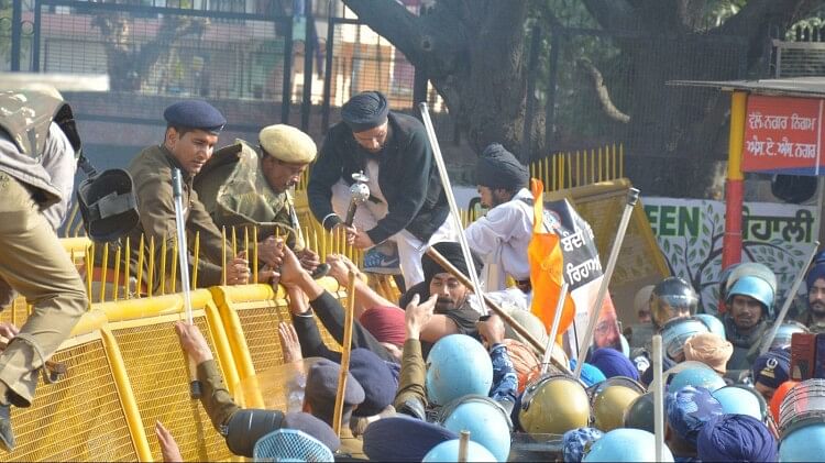 बैरिकेड पर चढ़ते प्रदर्शनकारी।