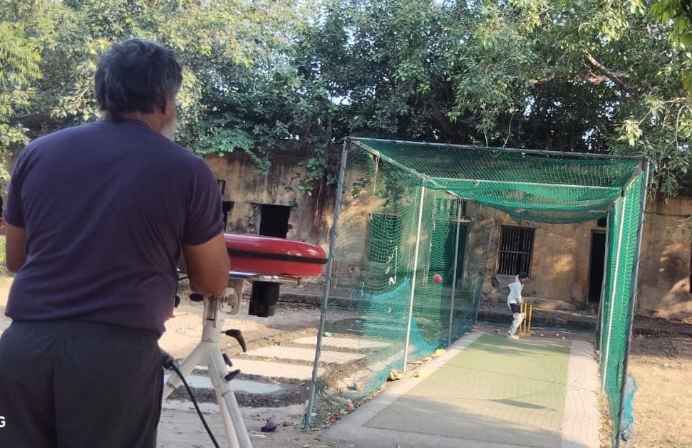 प्रशिक्षण शिविर में बल्लेबाज को बॉलिंग मशीन से अभ्यास कराते कोच। संवाद