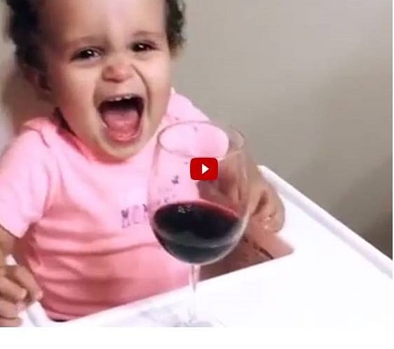 Dad gives baby girl a glass of wine