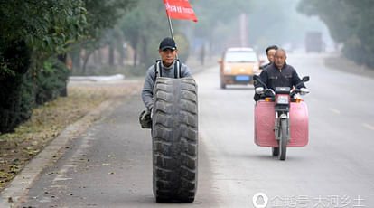 Wang Hao begun to walk from his hometown to Beijing rolling an old 135-kilogram tire