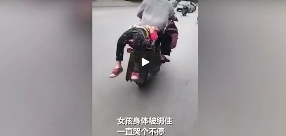 Father ties daughter to back of motorbike and drives her to school Video goes viral 