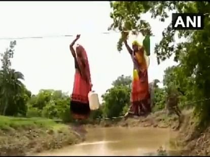 women crossing flooded river