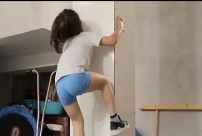 छोटी बच्ची दीवाल पर चढ़ते हुए