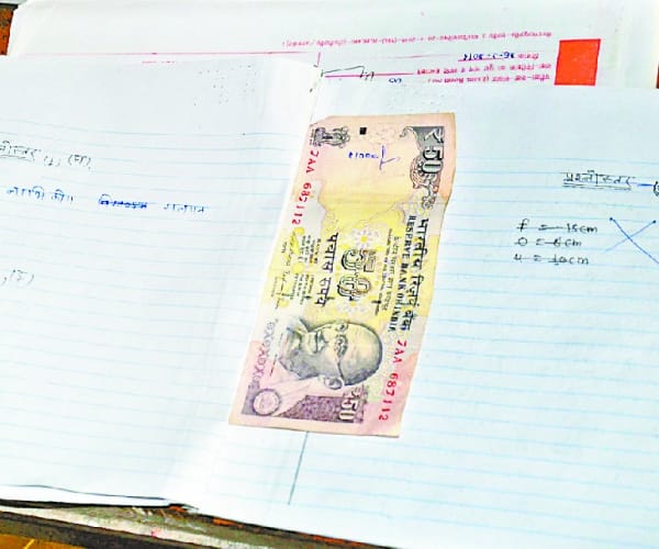 Money in students examination note book.