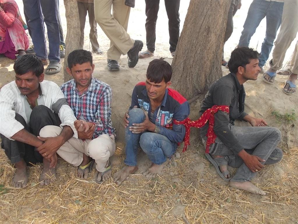 Villagers hold four rogues tied to tree