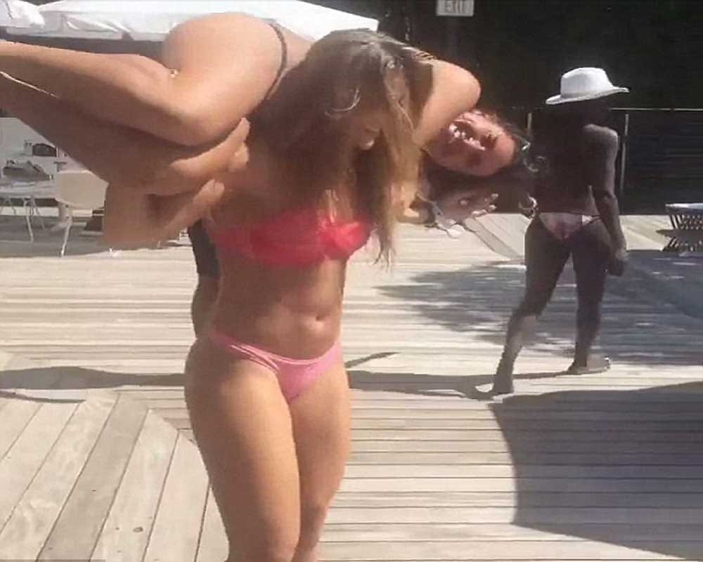 bikini girl performing squats with her friend