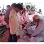 भूख हड़ताल पर बैठे बुजुर्ग का बीपी जांचते हुए स्वास्थ्य कर्मी।
