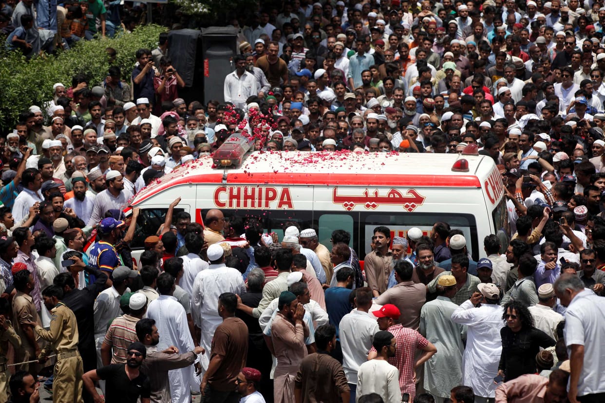 People throw flower petals on the ambulance carrying the body of Amjad Sabri