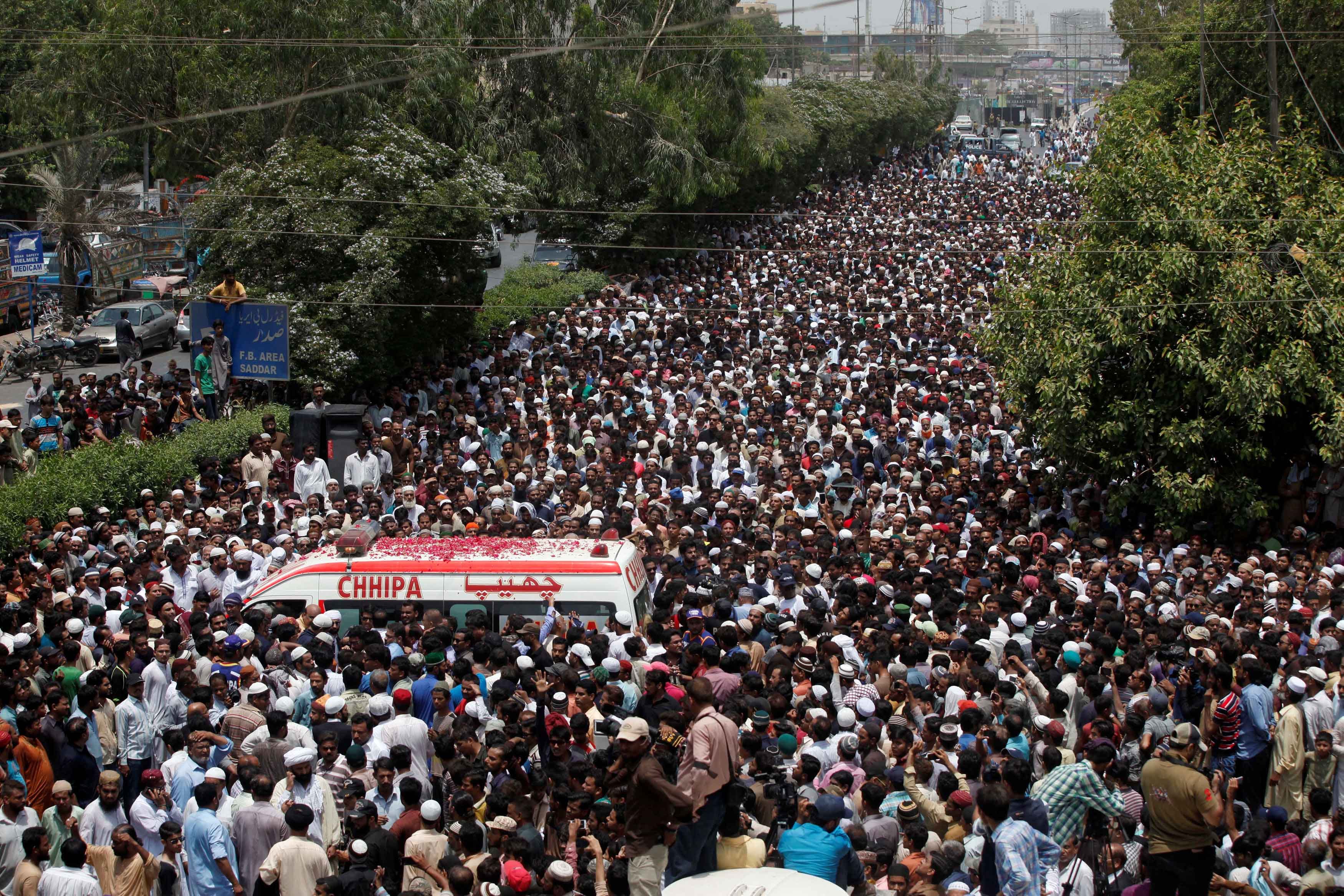 People throw flower petals on the ambulance carrying the body of Amjad Sabri