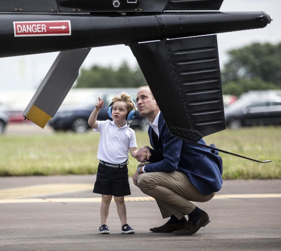 Prince George looks up at the tail rotor of a "Squirrel" helicopter 