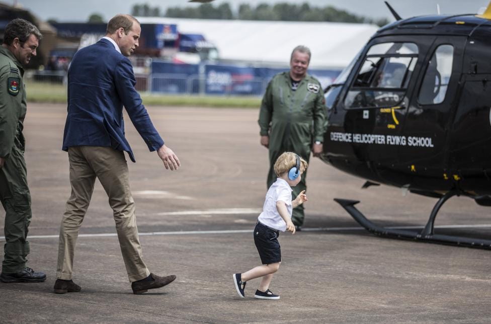 Prince George looks up at the tail rotor of a "Squirrel" helicopter 