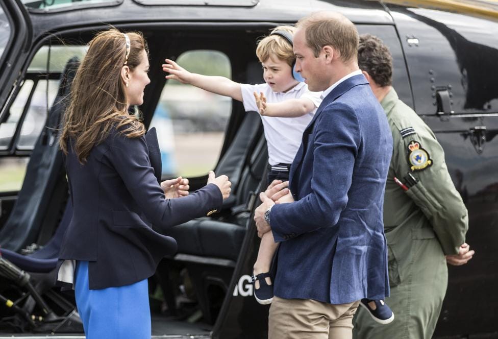 Prince George looks up at the tail rotor of a "Squirrel" helicopter 