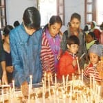 चर्च में कैंडल जलाते बच्चे।  