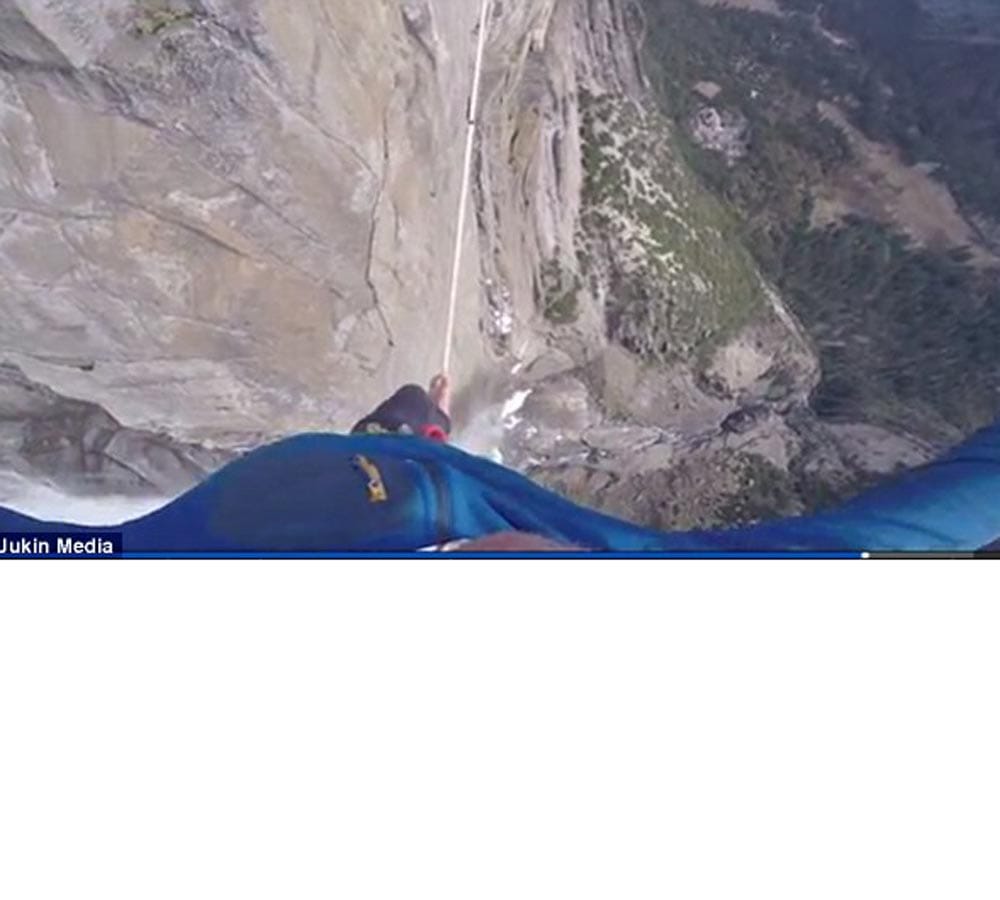 a man walks across 2500ft slackline above Yosemite Park's Upper Falls