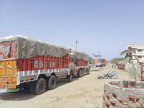 Six trucks carrying sand and holding a tractor