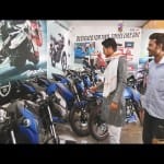 टीवीएस शोरूम में बाइक देखते ग्राहक।