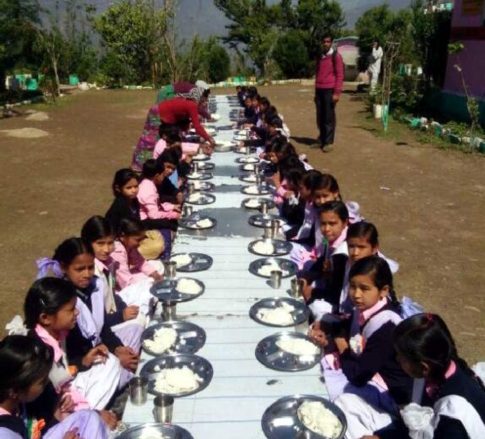 students eaten food at dining table in government school