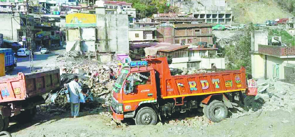 फोरलेन की जद में आए भवनों को उखाड़ने का काम जारी, आठ दुकानें तोड़ी