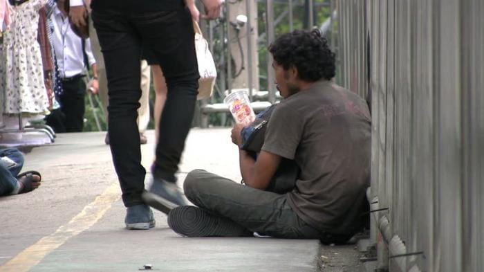 a man like a beggar is providing 100 dollar coin