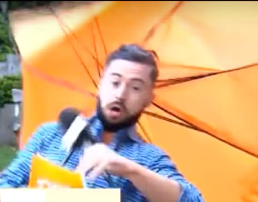Reporter Deric O hartagain blown by the wind during live telecast of weather reoprt in Dublin