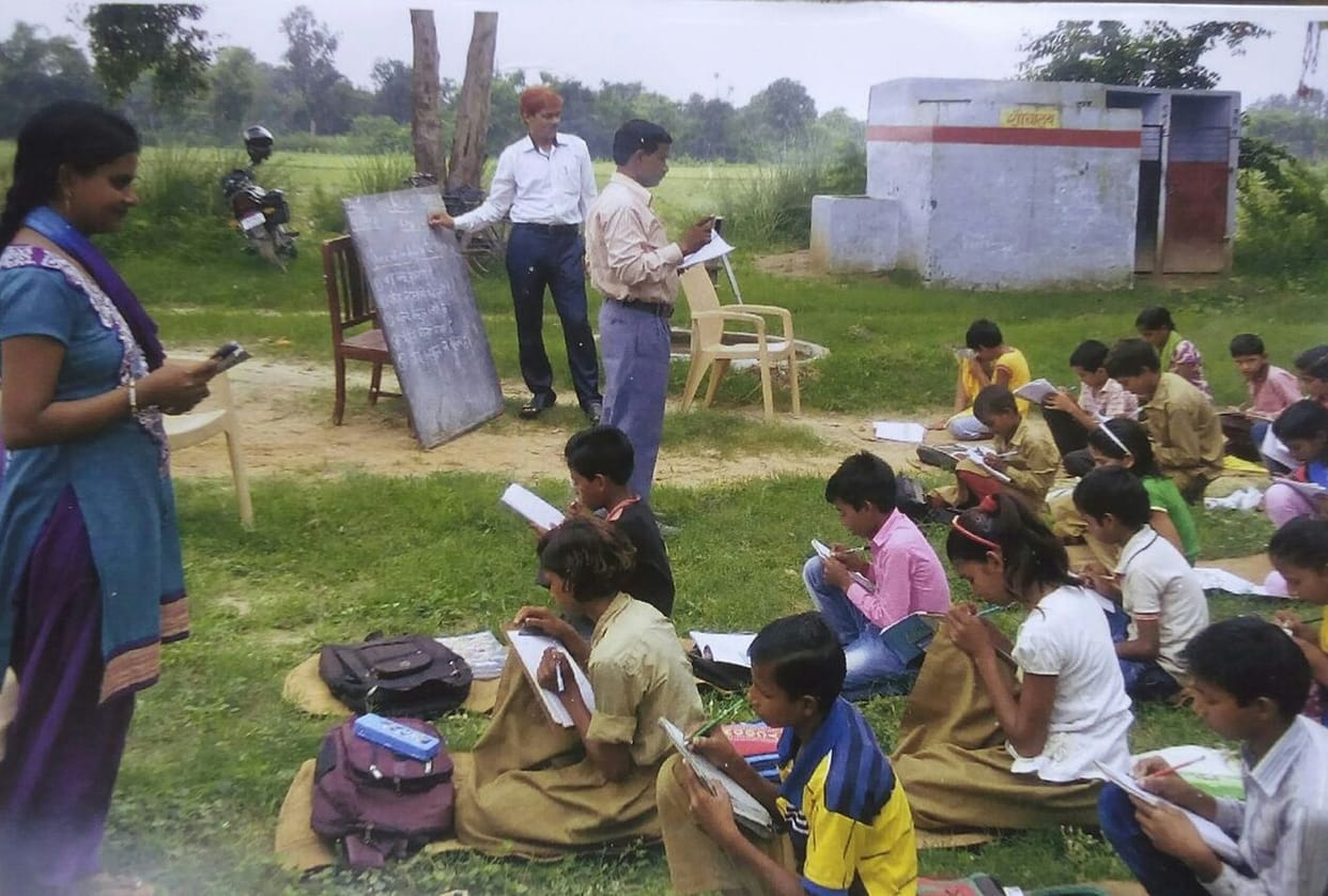 खुले आसमान के नीचे क, ख, ग पढ़ रहे बच्चे