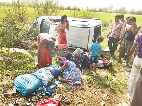 दुर्घटनाग्रस्त कार के समीप जमीन पर लेटे घायल