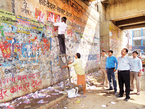 अकबरपुर में होर्डिंग पोस्टर हटवाते नगर पंचायत कर्मी