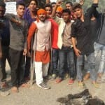 पुतला जलाते लोग।