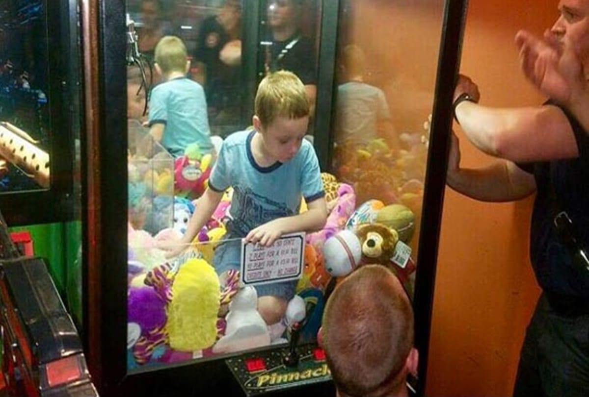boy climbs into toy claw machine and strucked into it firefighter save him