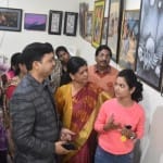 प्रदर्शनी में पेंटिंग देखने पहुंचे लोग।