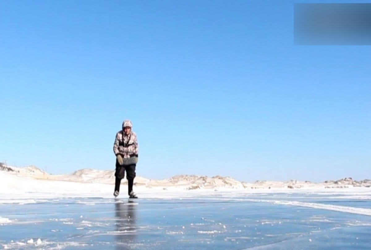 seventy years old grandma ice skates over a frozen lake in Siberia