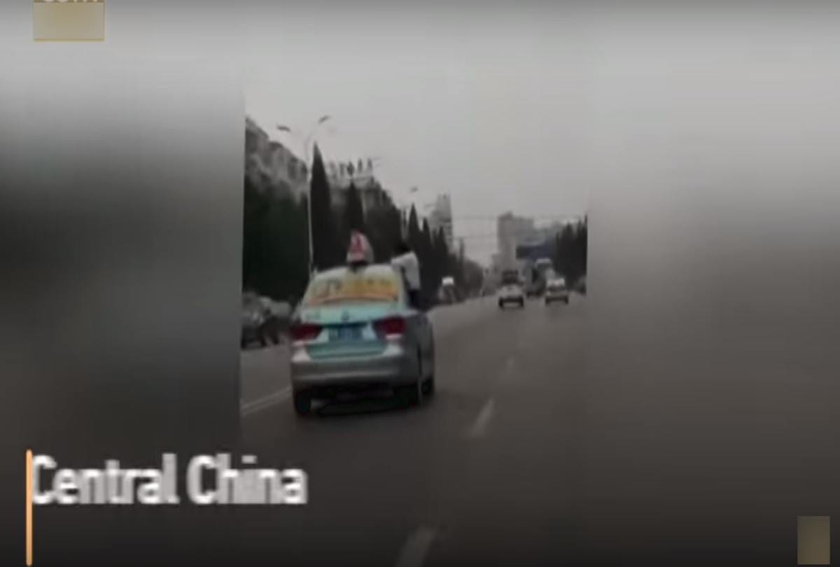 School girl caught doing homework on top speeding taxi roof on china