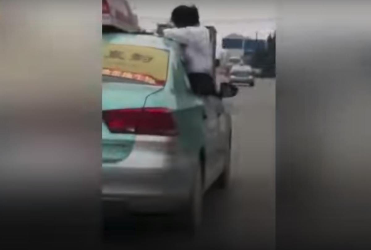School girl caught doing homework on top speeding taxi roof on china