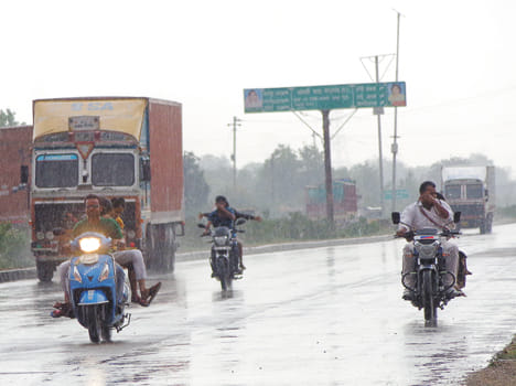  बारिश में भीगते हुए जाते राहगीर।
