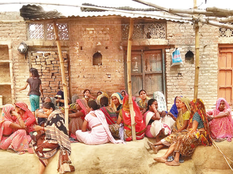 सुरजन पाल के घर के बाहर गमगीन बैठी महिलाएं।  