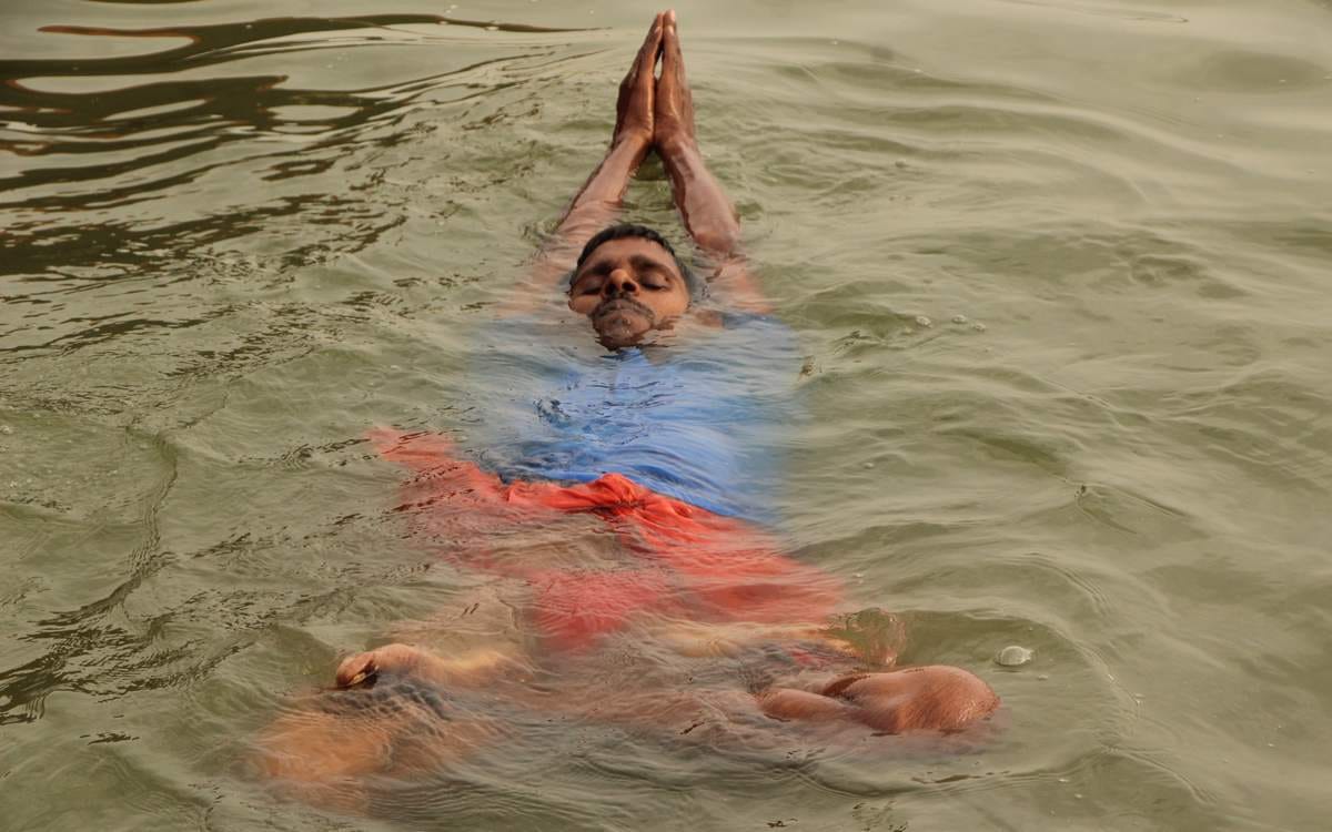Yoga practice in waves of ganga by a man in varanasi