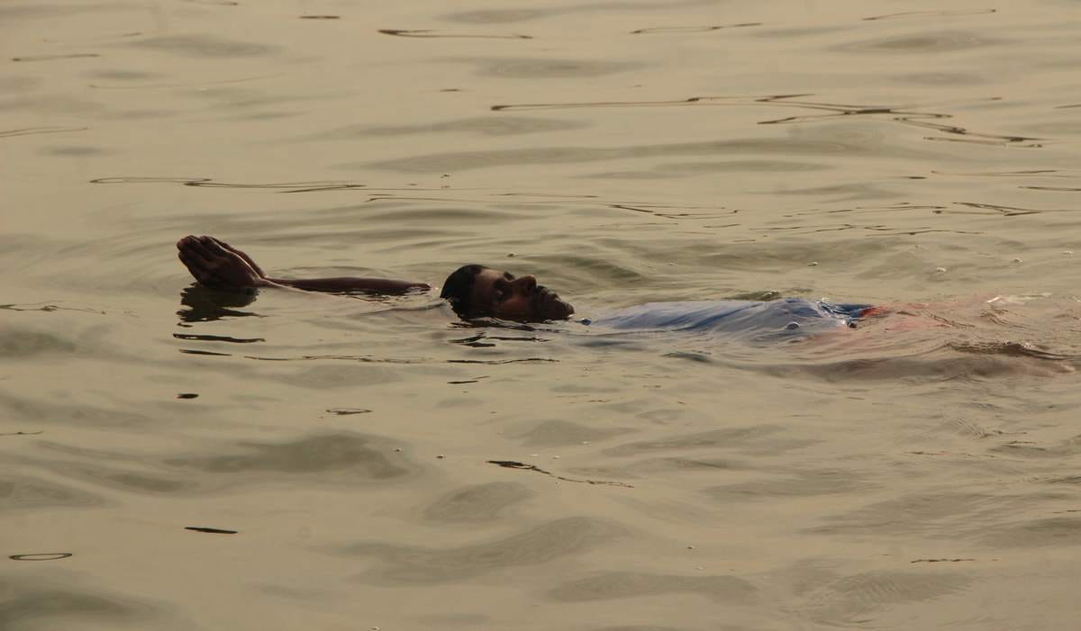 Yoga practice in waves of ganga by a man in varanasi
