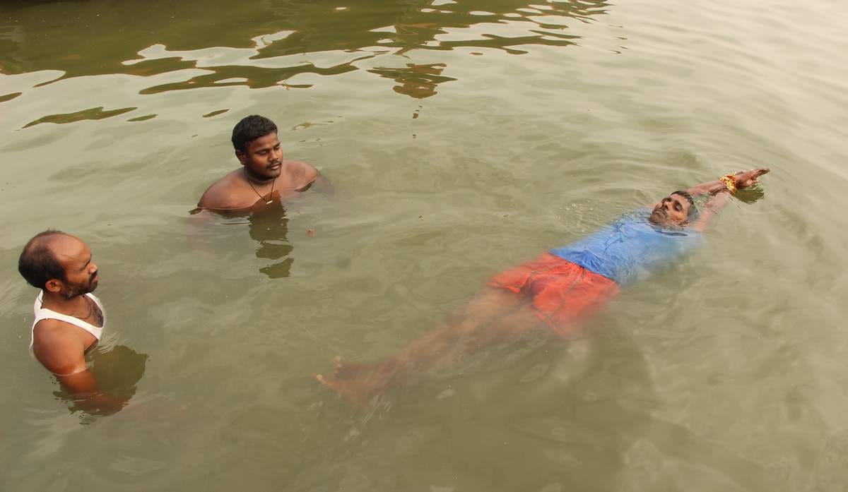 Yoga practice in waves of ganga by a man in varanasi
