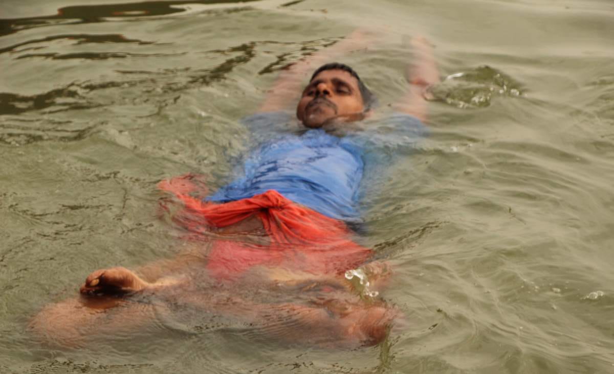 Yoga practice in waves of ganga by a man in varanasi