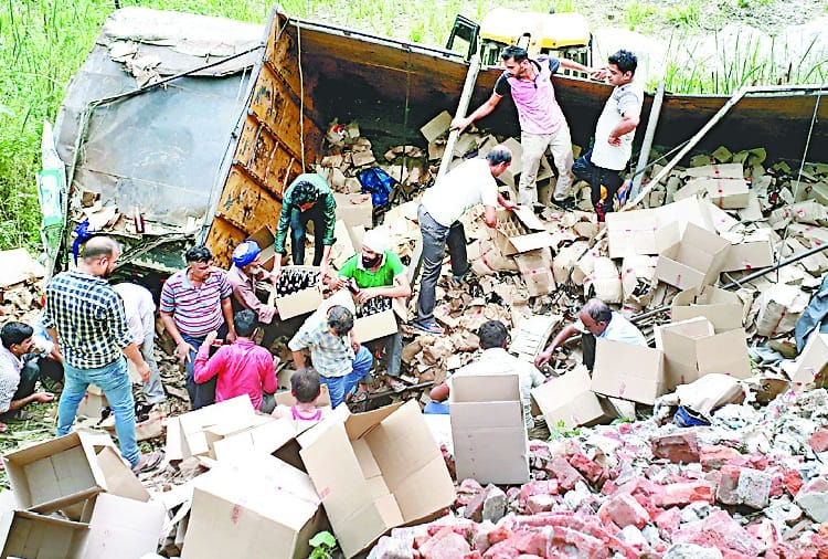 खाई में गिरा शराब का ट्रक, लोग पेटियां लेकर चलते बने