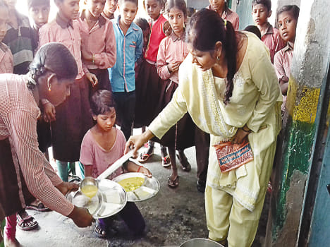 बच्चों को मिड डे मील वितरित करती रसोइया।