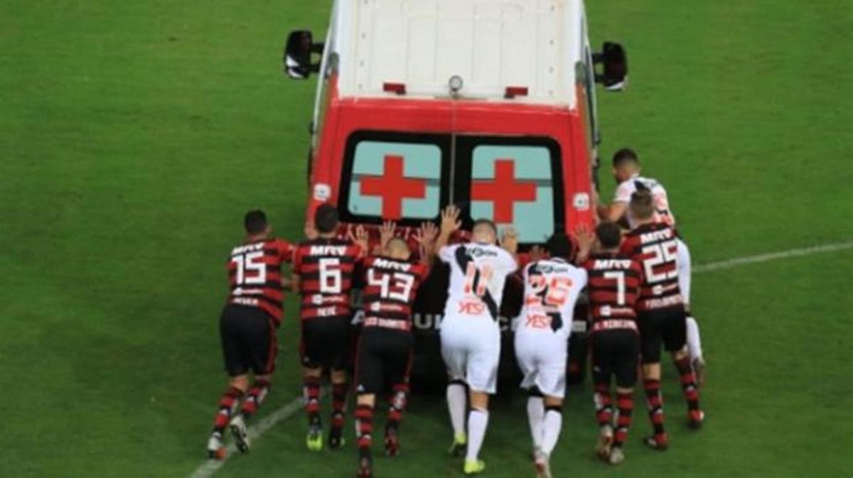 football rival team players get together to push ambulance for injured player