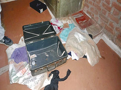 कमरे के भीतर खुली पड़ी अटैची और फर्श पर बिखरा सामान।