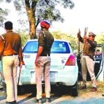 कार से लाठी-डंडा बरामद करती पुलिस
