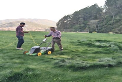 Anil Sharma is cutting grass in the lawn of his new house in Mandi