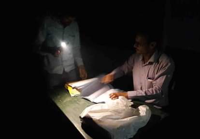 मोबाइल टॉर्च की रोशनी में कागजी कार्यवाही पूरी करते मतदान कार्मिक