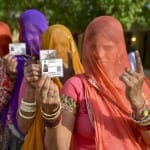 सोमवार को मतदान करने से पहले वोटर आईडी दिखातीं महिलाएं