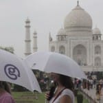 ताजमहल पर बूंदाबांदी के बीच छाता से बचाव करते सैलानी